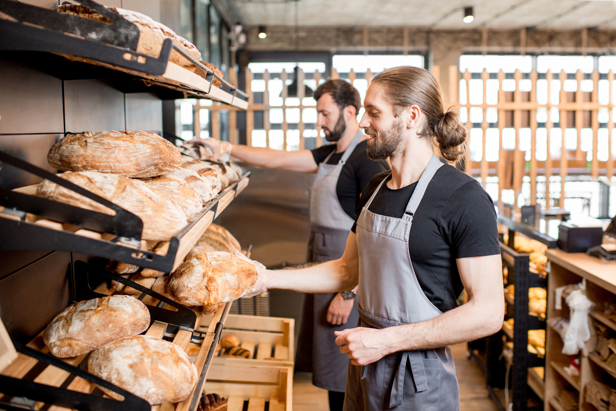 two men with shelves of bread in a bakery