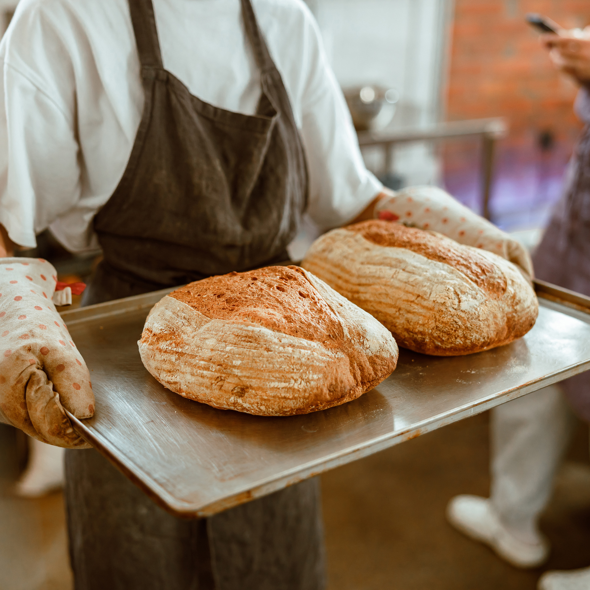 woman holding fresh baked bread on a pan