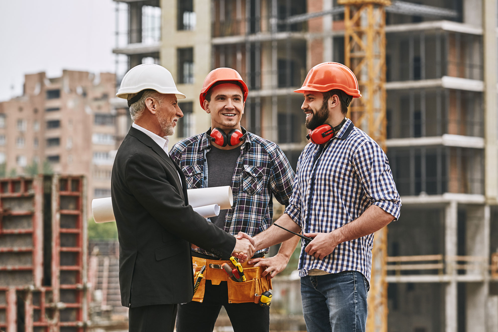 construction workers shaking hands with business man at building site