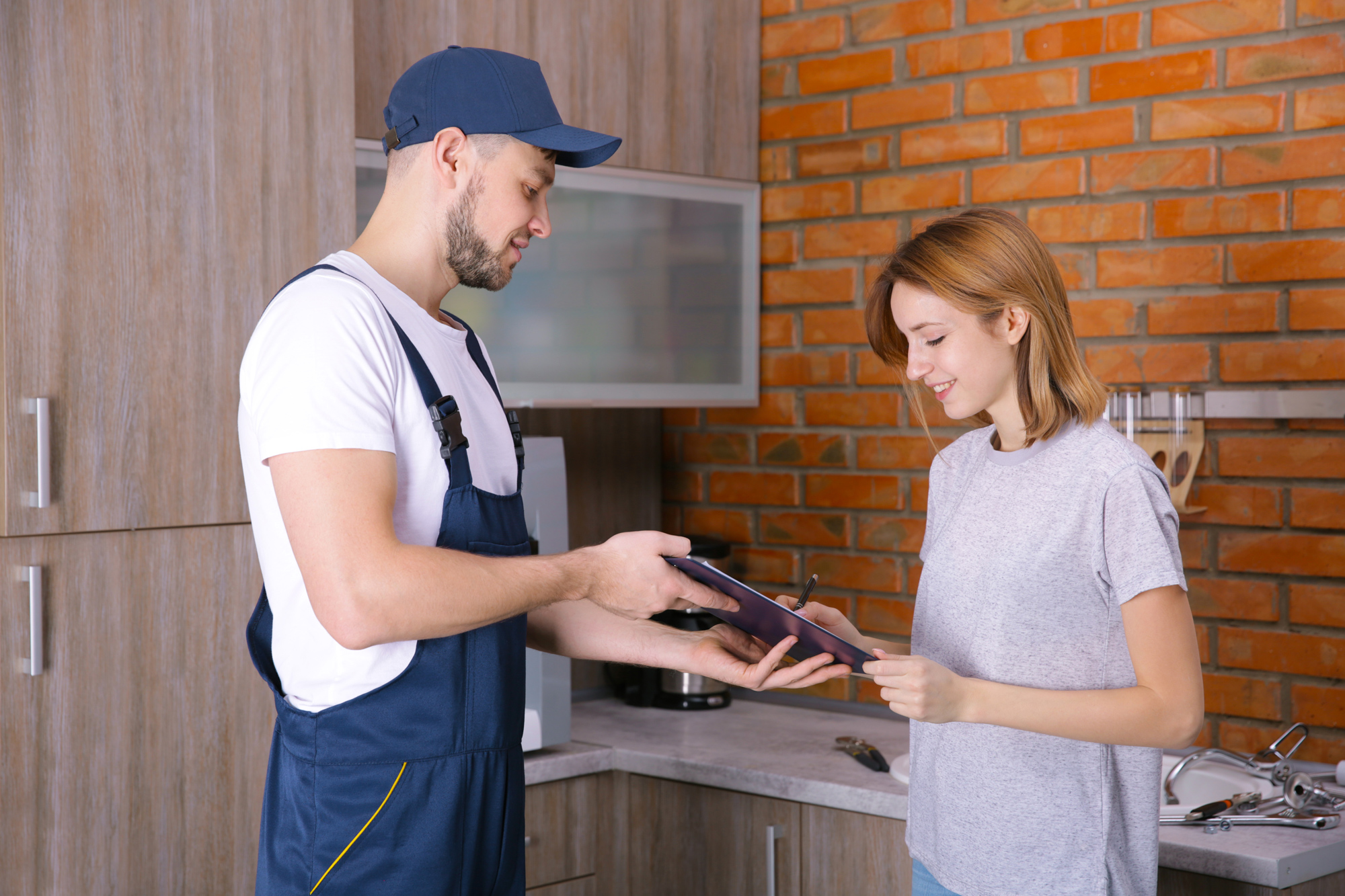 man plumber talking to woman client signing document