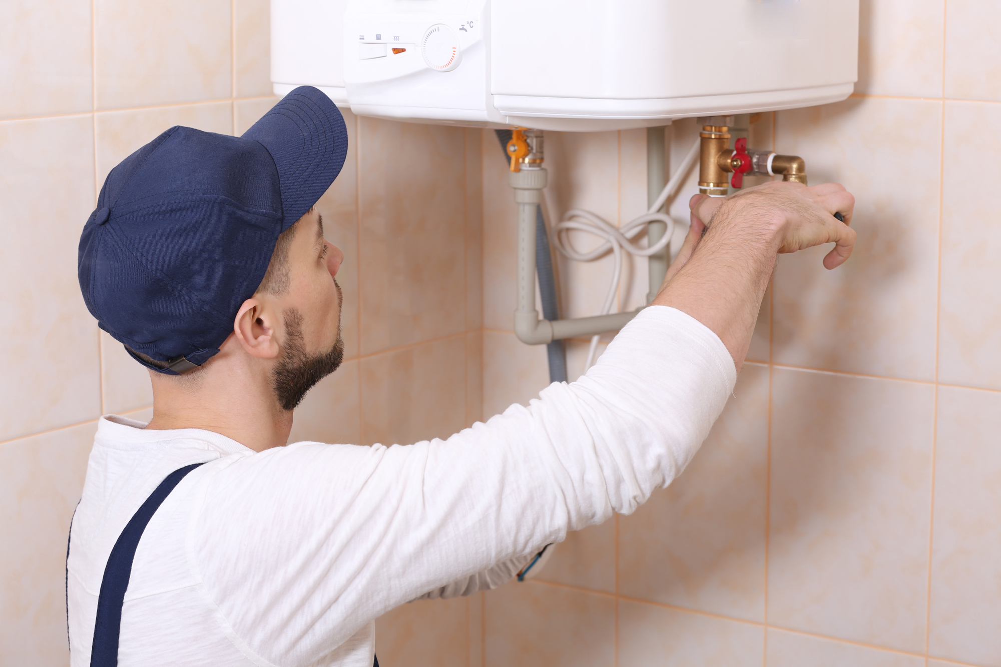 man plumber fixing pipes under sink with wrench